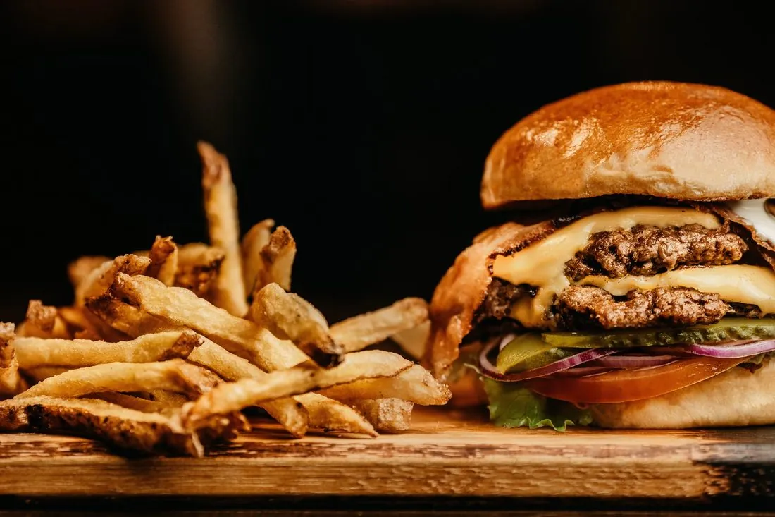 Burger ŻAR z frytkami na drewnianej desce
